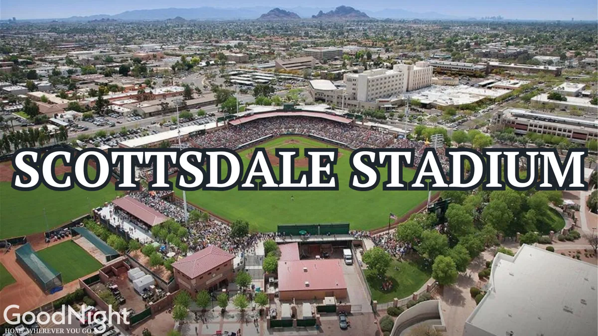 This image captures a vibrant baseball field filled with a crowd of spectators, surrounded by buildings and mountains in the background. The energy is palpable as fans watch a lively game, perfectly evoking the atmosphere of Scottsdale Stadium and the buzz of Spring Training.