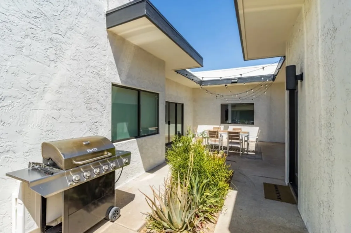 This image showcases a backyard setting with a grill, dining table, and thoughtfully landscaped surroundings. The setup is ideal for outdoor dining, barbecues, and relaxed gatherings, reinforcing the idea of flexible group accommodations.